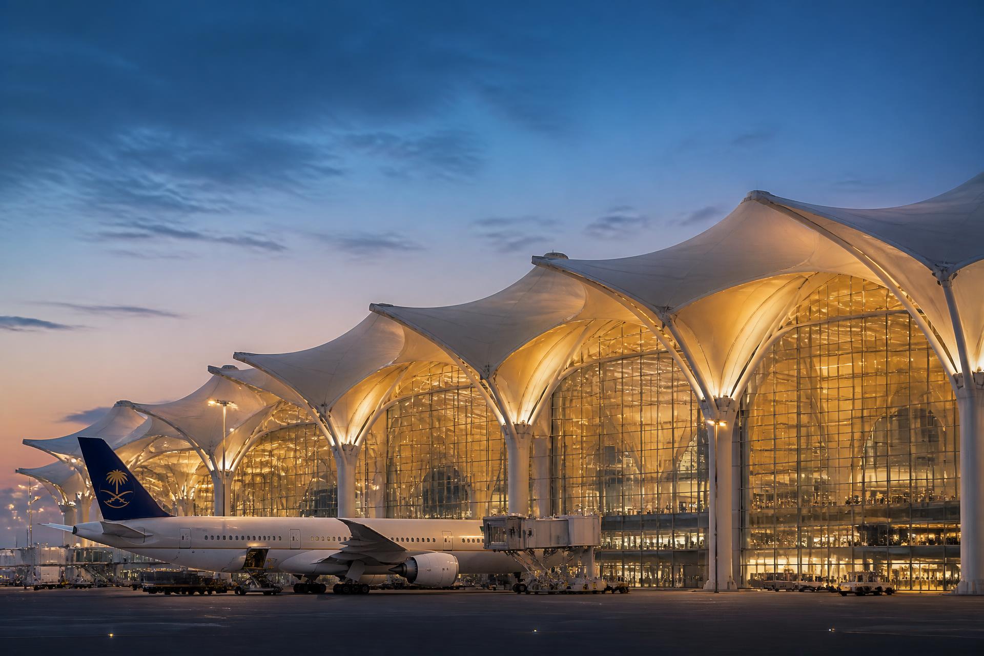 مطار الملك عبدالعزيز الدولي عند الغسق — هندسة خيام بيضاء مضاءة من الداخل